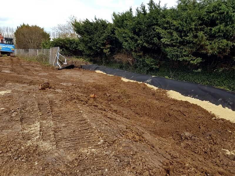 HDPE barrier sheeting installed edge-on in a trench along a hedge line to block root spread
